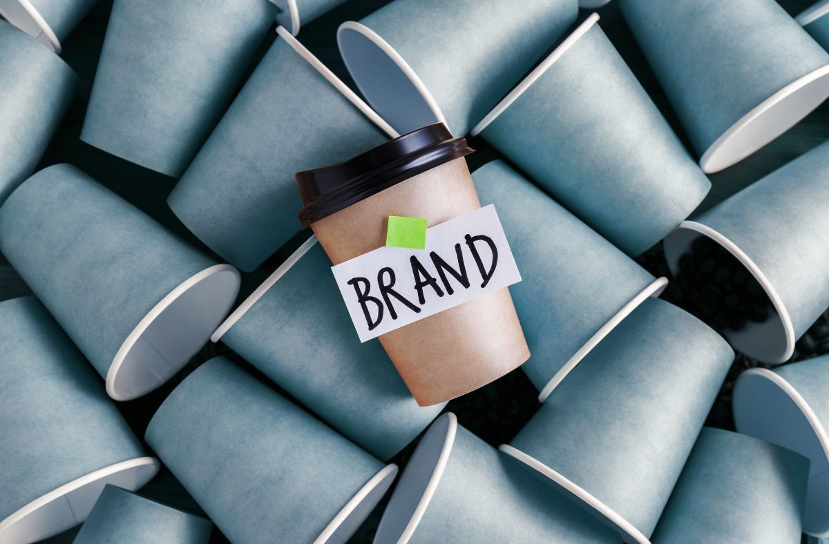 Image of plain blue disposable coffee cups with a single brown cup with the word 'brand' afixed.