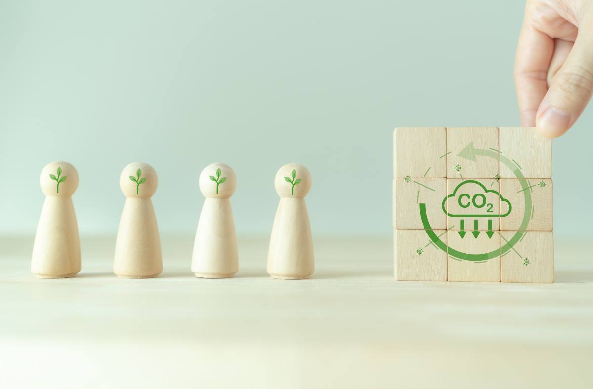 Wooden figures and building blocks with a carbon reduction symbol.