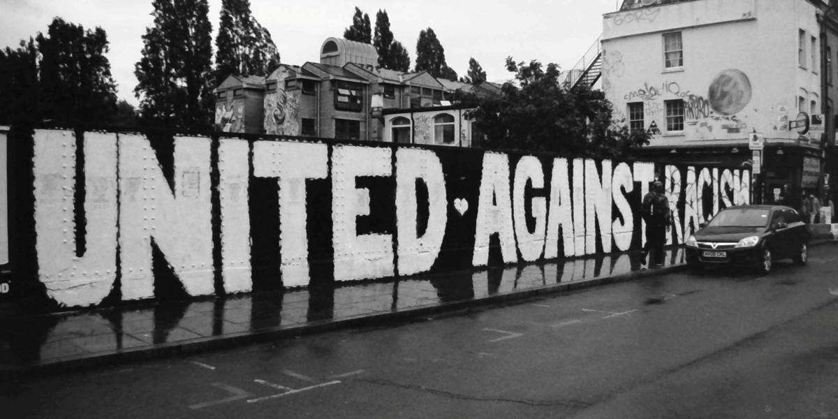 Black-and-white photograph of a street mural reading “UNITED AGAINST RACISM”.